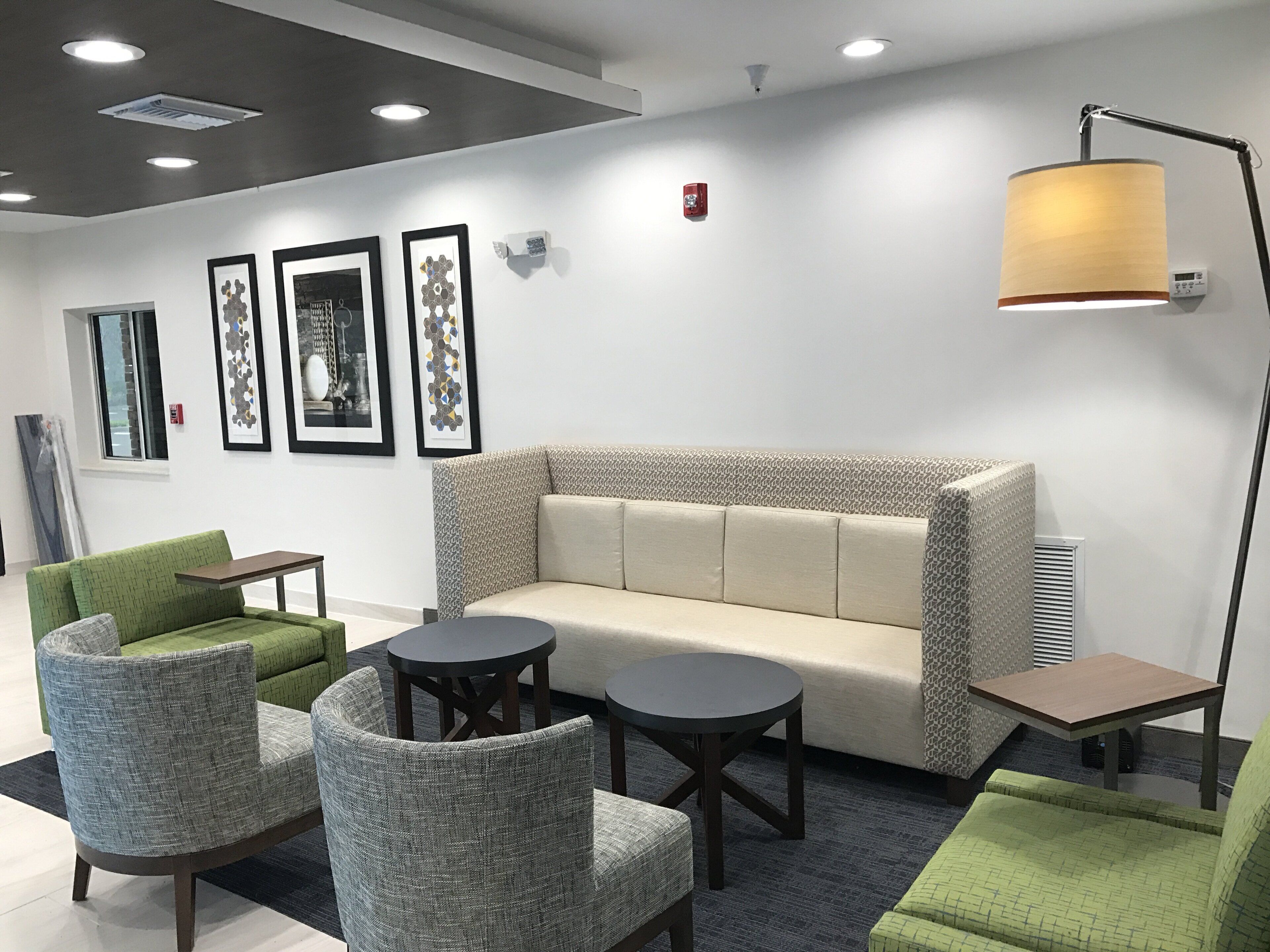 A modern lounge area with a sofa, chairs, tables, and artwork on the walls.