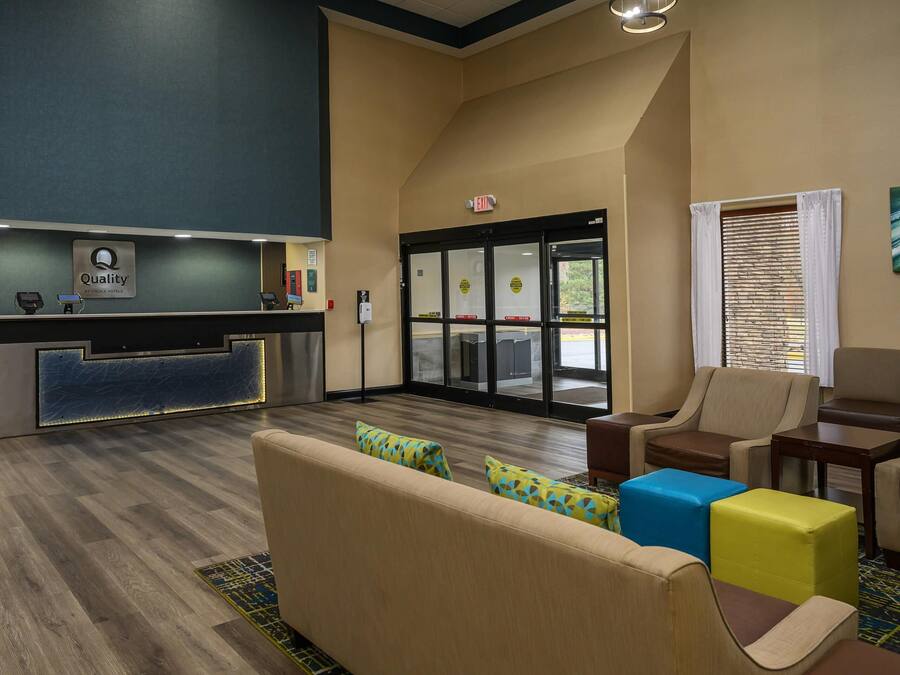 A hotel lobby with a reception desk, seating area, and a view of the outside.