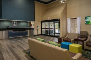 Un hall de hotel con mostrador de recepción, zona de estar y vistas al exterior.