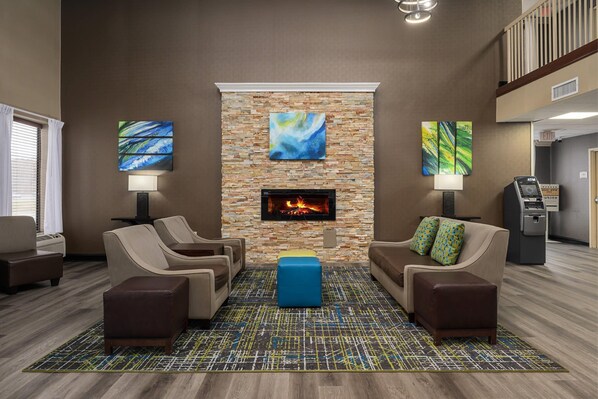 A lobby with a fireplace, seating area, and ATM.