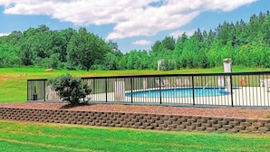 Piscina cercada con vistas despejadas de la vegetación y árboles circundantes.