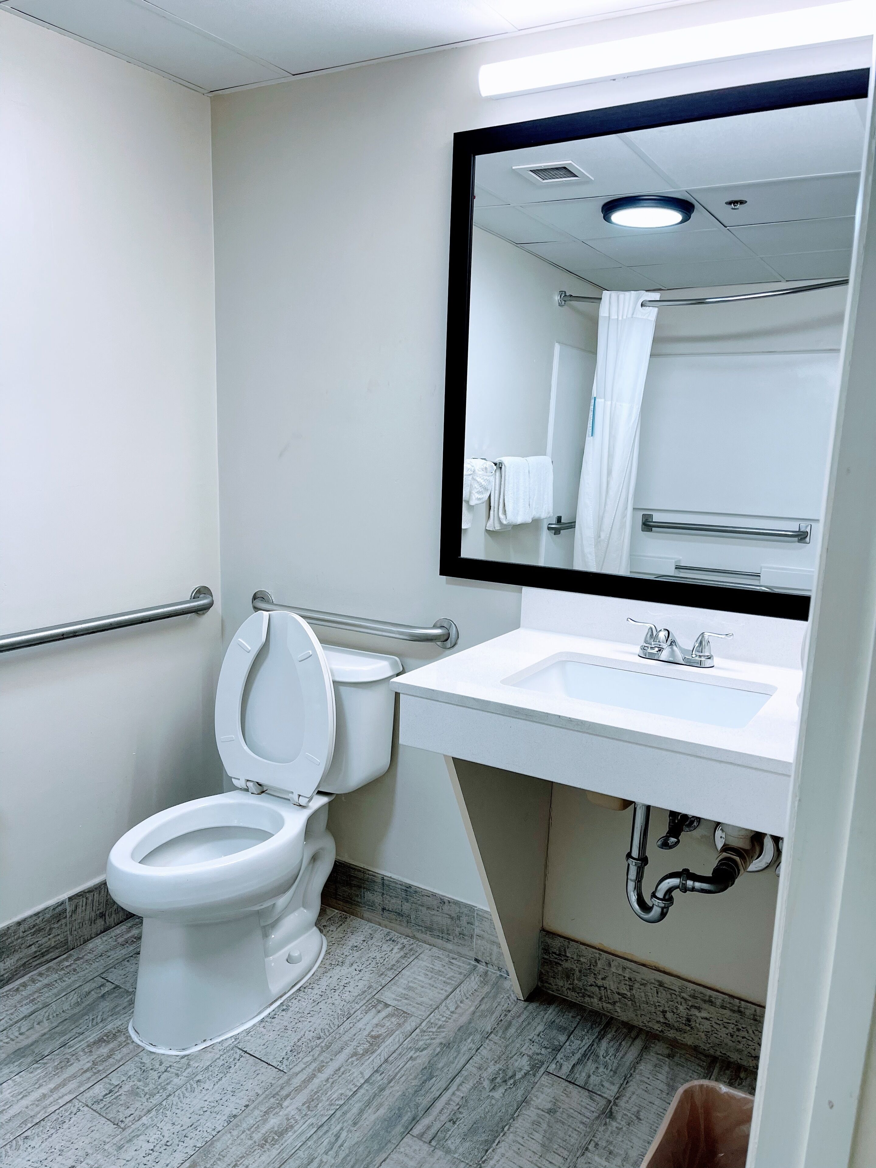 Un baño con inodoro blanco, lavamanos con espejo y cortina de ducha.