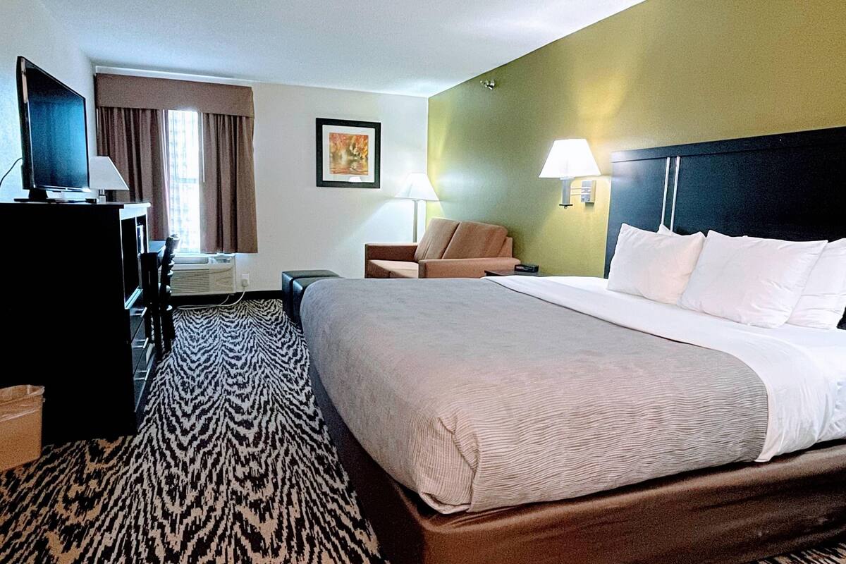 Una habitación de hotel con una cama, un escritorio, un televisor y una silla.