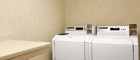 A laundry area with two white front-loading washing machines and a beige countertop.