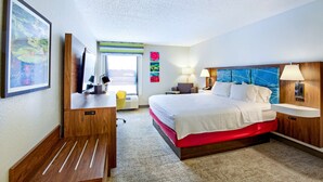 A hotel room with a large bed, a desk, a chair, a desk lamp, a bedside table, and a window with a view. - Hampton Inn Slidell (Slidell)