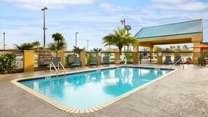 A swimming pool with lounge chairs and a covered area with a clear sign indicating a 124-foot clearance. - Hampton Inn Slidell (Slidell)