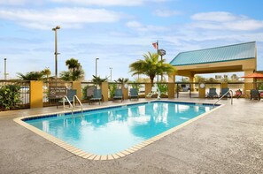 A swimming pool with lounge chairs and a covered area with a clear sign indicating a 124-foot clearance. - Hampton Inn Slidell (Slidell)
