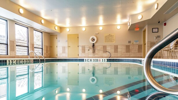 Una piscina interior con marcas de carriles claramente definidas, una silla de salvavidas y una escalera de piscina.