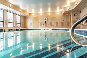 An indoor swimming pool with clear lane markings, a lifeguard chair, and a pool ladder.