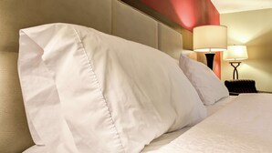 Una cama bien hecha con sábanas blancas y un cabecero.