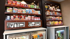 Zona de venta automática con aperitivos y bebidas, que ofrece diversas opciones de comida y refrigeradores expendedores.