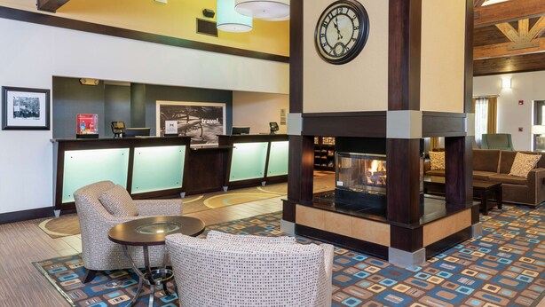 A lobby with a reception desk, seating area, and a fireplace.