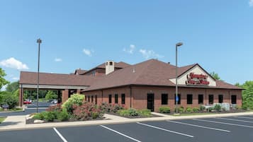 Hampton Inn & Suites features a brick facade and a pitched roof, with ample parking and a serene natural setting.