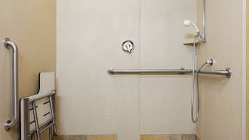 A handicap-accessible shower stall with a grab bar, a wheelchair lift, and a handheld showerhead.