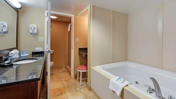 Une salle de bain d’hôtel équipée d’un lavabo, d’un miroir, d’un porte-serviettes et d’une baignoire.