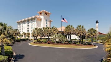 A hotel with a prominent American flag, palm trees, and a lighthouse in the background.
