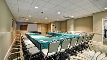 A conference room with a long table, chairs, and a projector screen.