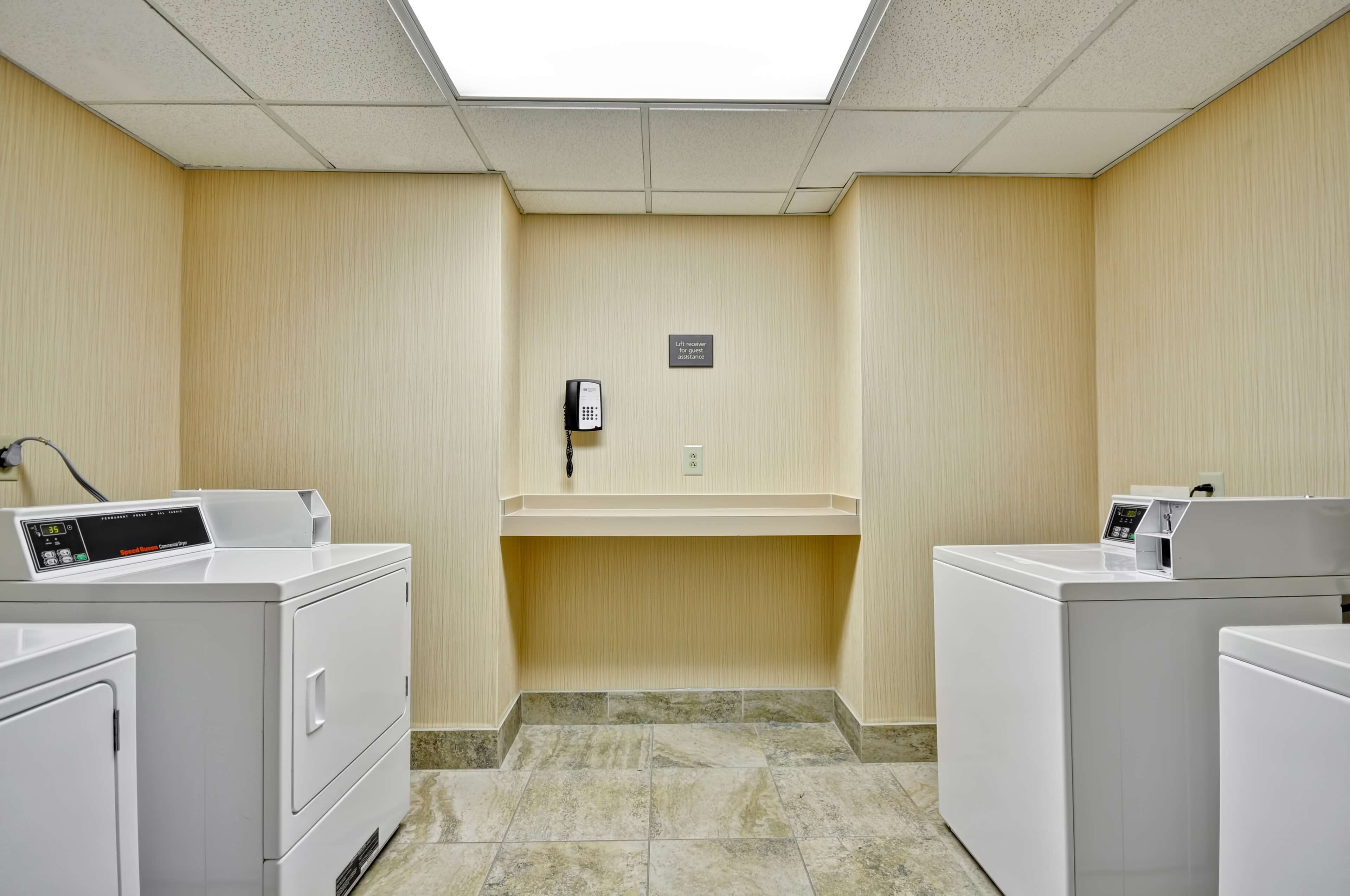 A laundry room with two washing machines, a phone, and a sign on the wall.