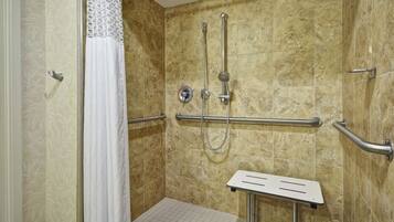 Un área de ducha con barra de apoyo, ducha y barandilla.