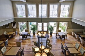 A spacious dining area with multiple tables and chairs, large windows, and potted plants. - Hampton Inn & Suites Charleston/Mt. Pleasant-Isle Of Palms (Mount Pleasant)