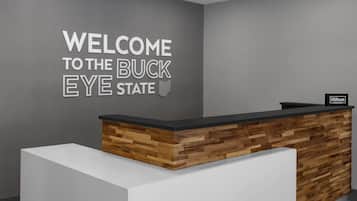 Un mostrador de recepción con un cartel que dice "WELCOME TO THE BUCK EYE STATE", una pared decorativa de madera y el logotipo de Hilton Honors.