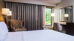 A hotel room with a large bed, a desk, a chair, a lamp, and a window with curtains. - Hampton Inn Philadelphia/Great Valley/Malvern (Malvern)