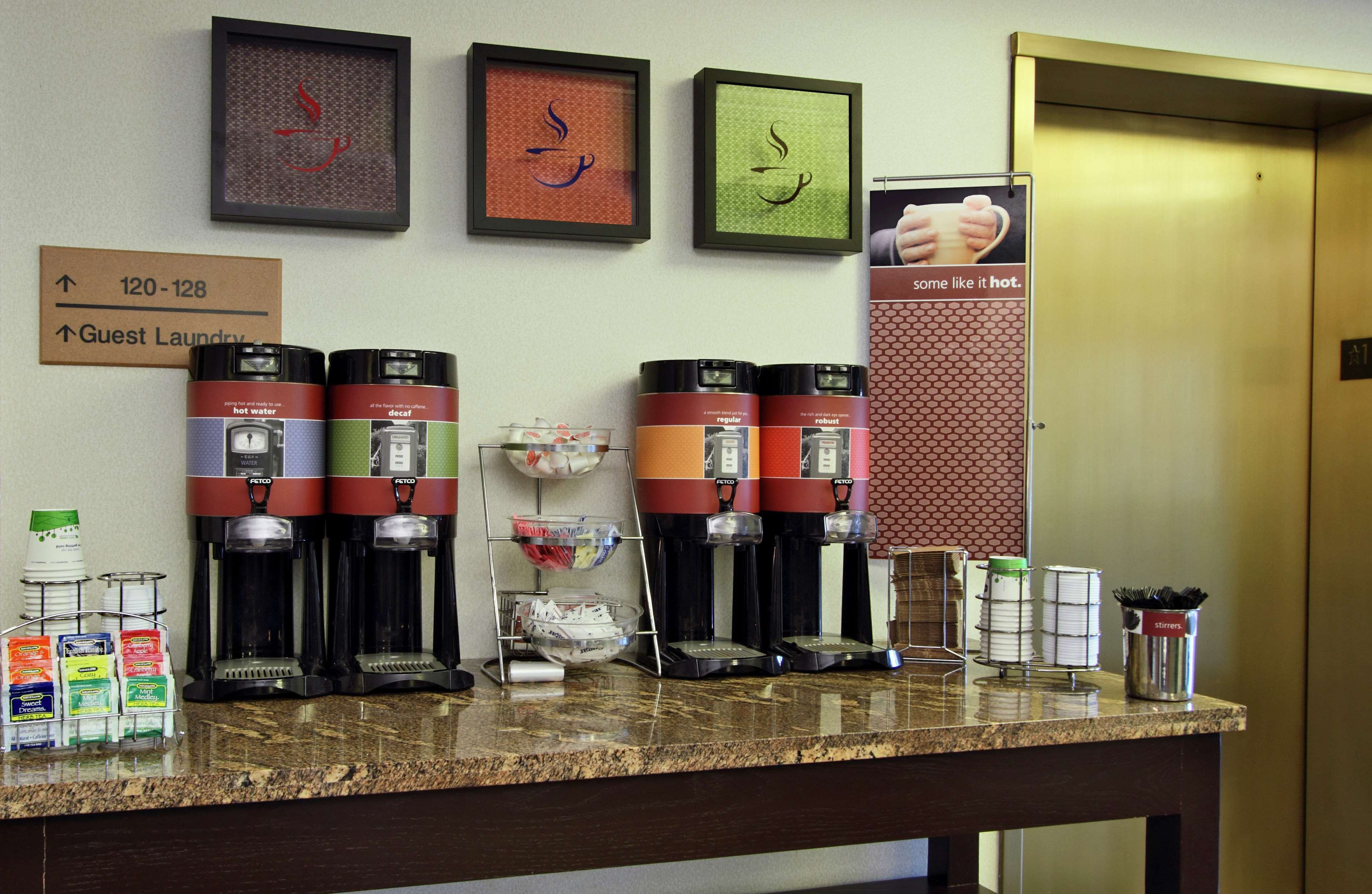 Un espace dédié au café, équipé de plusieurs machines à café, et une signalétique indiquant l’emplacement de la laverie pour les clients.