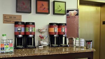 Un espace dédié au café, équipé de plusieurs machines à café, et une signalétique indiquant l’emplacement de la laverie pour les clients.