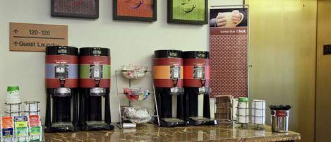 A coffee station with multiple coffee makers and a sign indicating guest laundry.