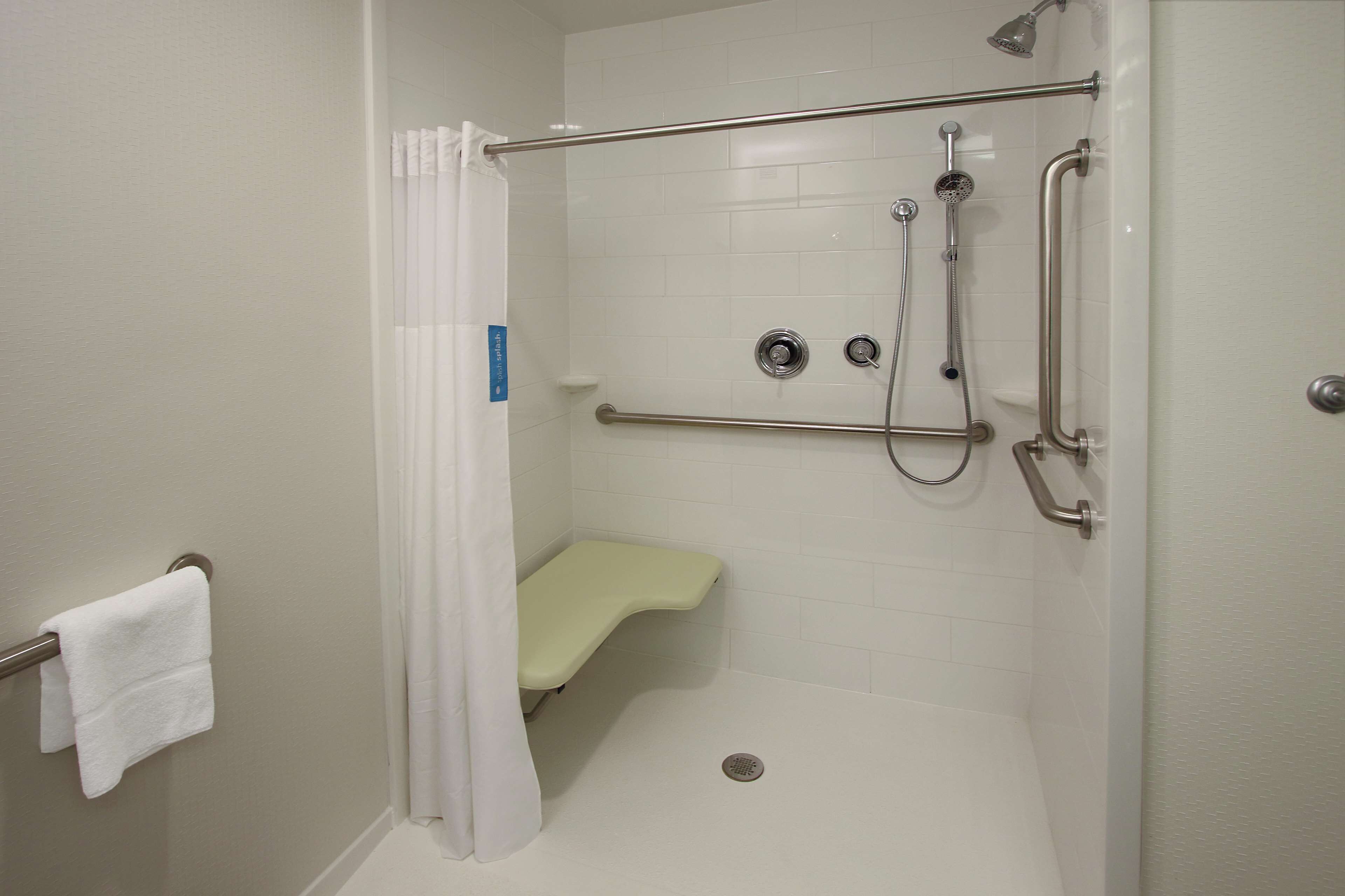 Eine barrierefreie Dusche mit Haltegriff, Sitzbank und Duschkopf.