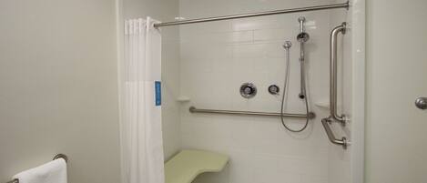 A walk-in shower with a grab bar, a bench, and a showerhead.
