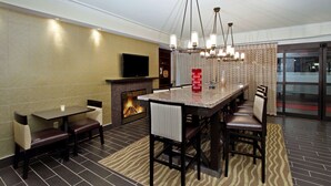 A modern lounge area with a fireplace, a television, and a dining table with chairs. - Hampton Inn Philadelphia/Great Valley/Malvern (Malvern)