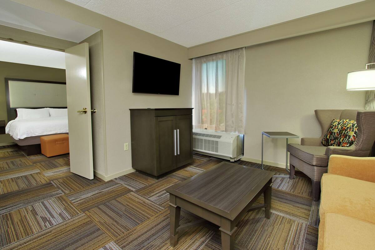 A hotel room with a bed, a TV, a desk, and a sofa.