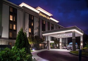 A Hampton Inn hotel with a well-lit entrance, a covered parking area, and a clear signage.