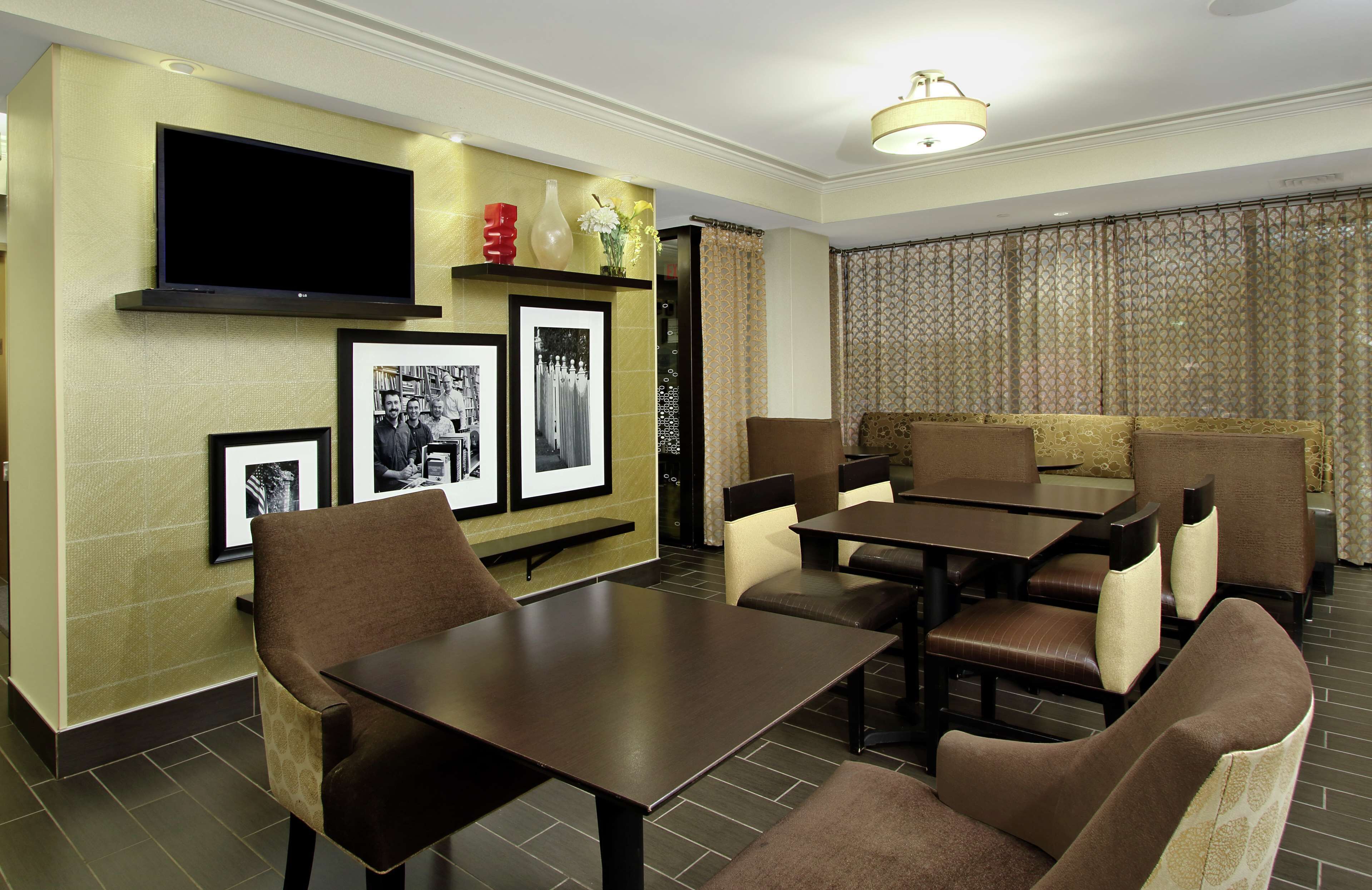 A dining area with a TV mounted on the wall, framed pictures, and a sofa set.