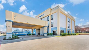 A Comfort Inn hotel with a covered parking area, a stone pillar, and a clear blue sky.