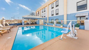 A swimming pool with lounge chairs, a changing room, and a building with multiple windows.