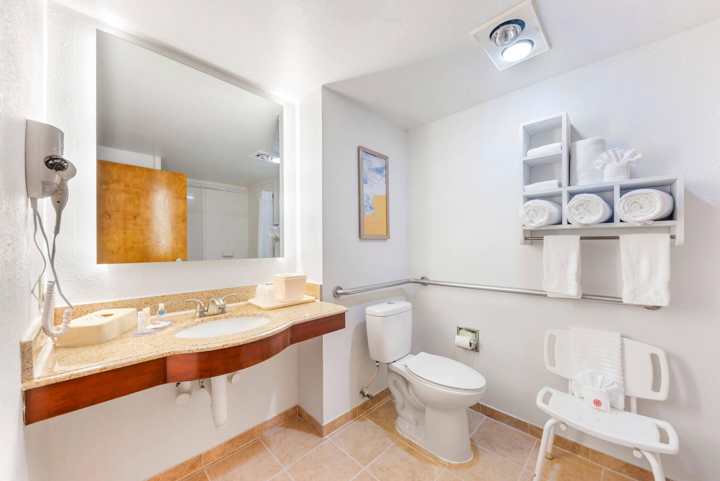 Un baño con lavamanos, inodoro y repisa con toallas.