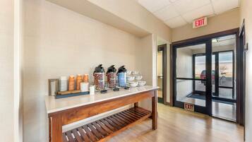 A reception area with a coffee station, a wooden bench, and an exit sign.