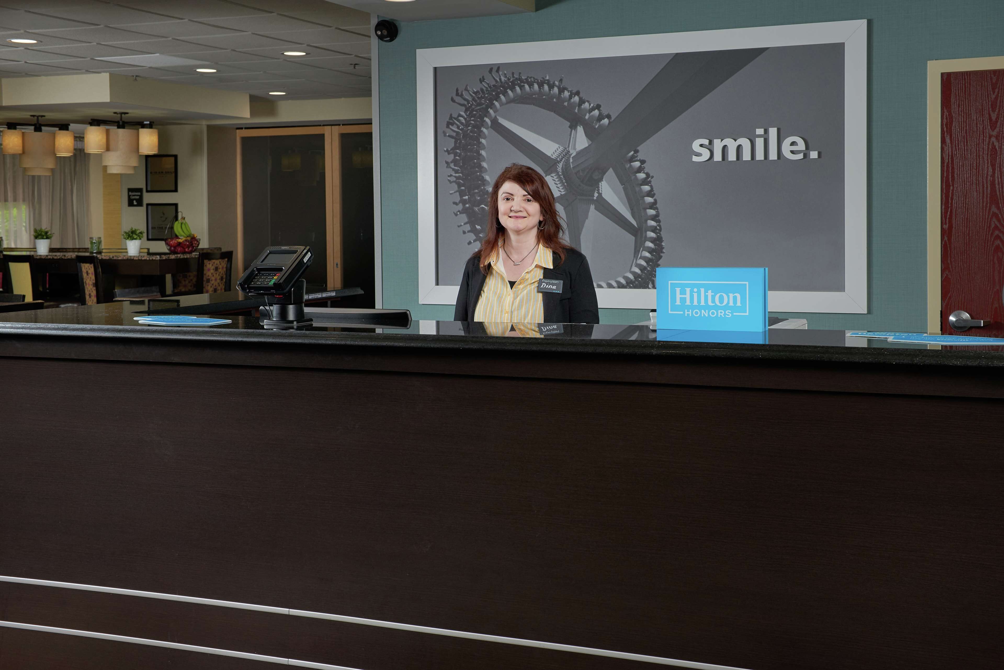 Una mesa de recepción de hotel con un cartel grande que dice "smile" y "Hilton Honors".