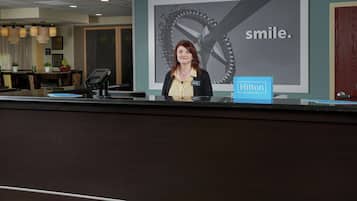 Una mesa de recepción de hotel con un cartel grande que dice "smile" y "Hilton Honors".