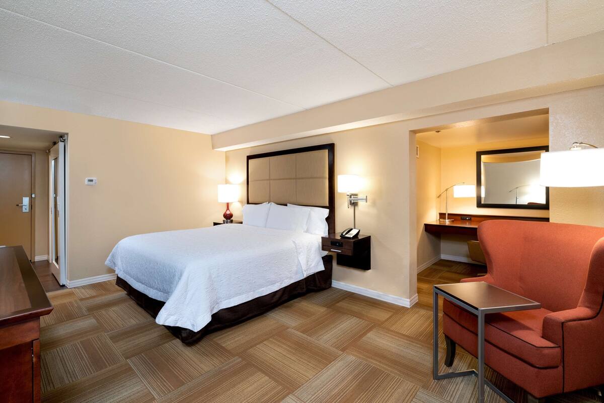 A hotel room with a large bed, bedside lamps, a desk, and a chair.
