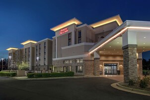 A Hampton Inn Suites building with a modern design, featuring a prominent entrance and a well-lit facade.