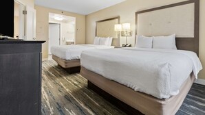 Habitación de hotel con dos camas, un escritorio y un espejo.