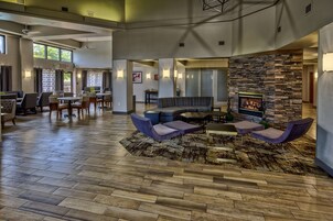 A spacious lobby with a stone fireplace, seating area, and a dining section.