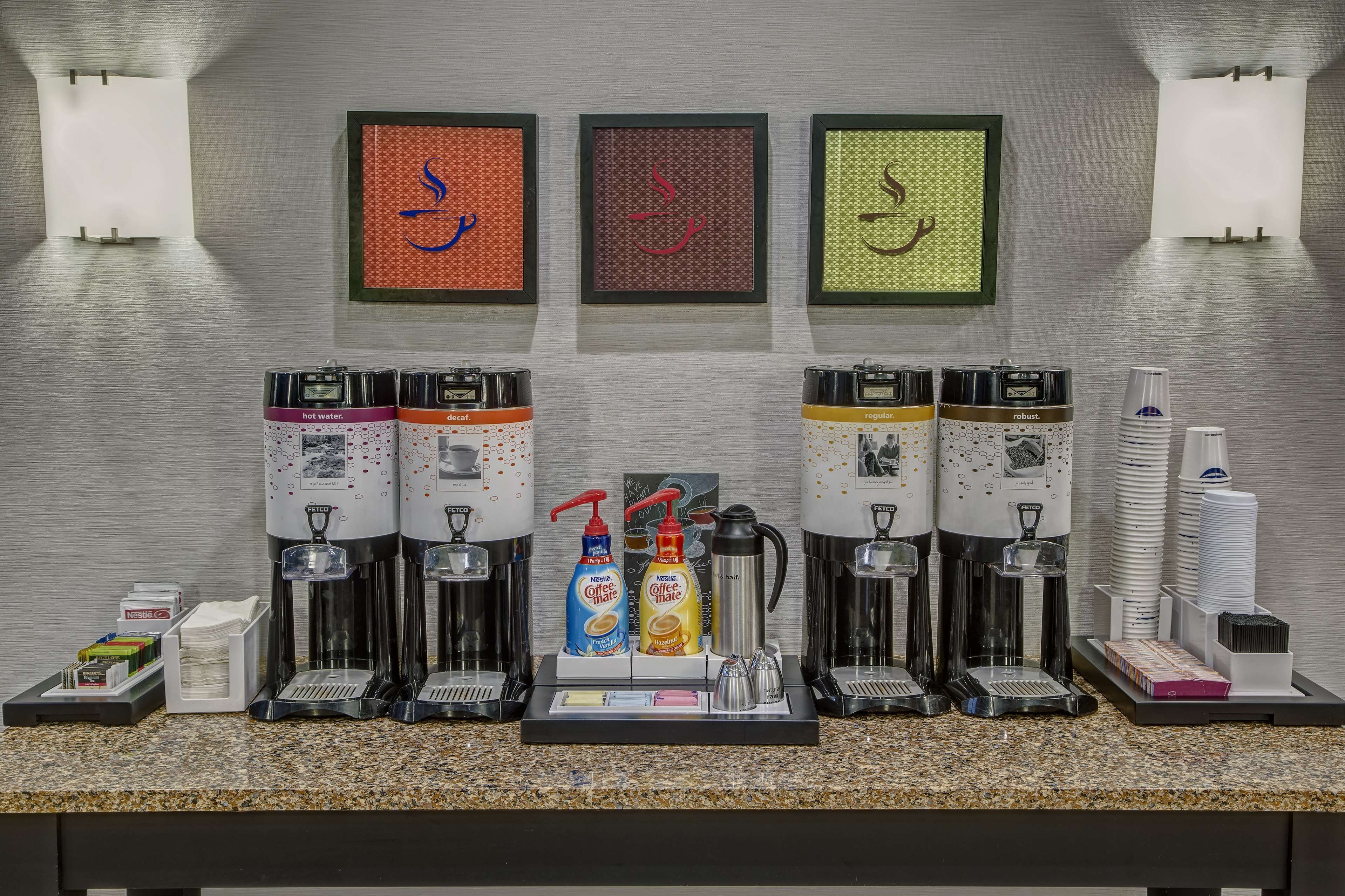 Una estación de café con varios dispensadores, una botella de detergente para platos y una botella de jabón para manos.