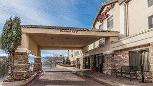 A hotel entrance with a clearway sign, stone pillars, and a bench. - Hampton Inn Colorado Springs-Airport (Colorado Springs)