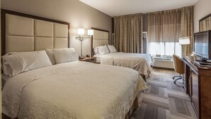 A hotel room with two beds, a desk with a television, and a large window with curtains. - Hampton Inn Colorado Springs-Airport (Colorado Springs)