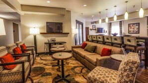 A hotel lobby with a seating area, a dining table, and a television. - Hampton Inn Colorado Springs-Airport (Colorado Springs)