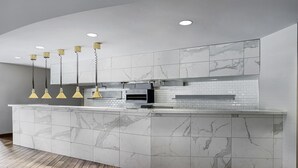 Une cuisine moderne avec un dosseret en marbre, un îlot central et des luminaires suspendus.